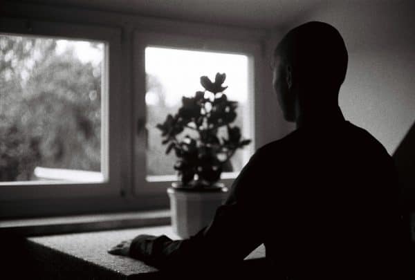 Man Staring out of window with plant pot