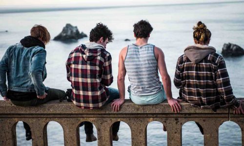 Group of young people sitting on bridge edge