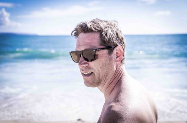 Man at beach with sunglasses and no shirt